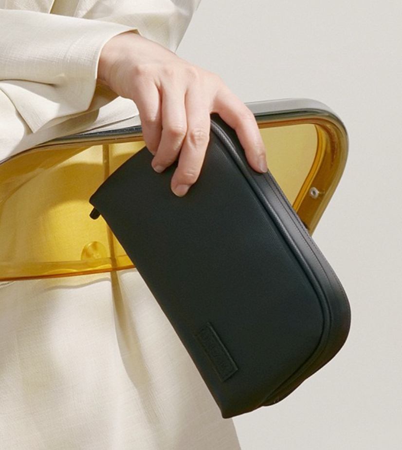 Person holding a black travel case with a neutral background